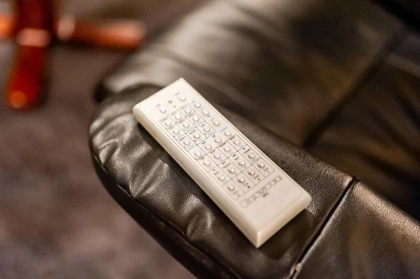 A remote control sitting on top of a black leather chair.