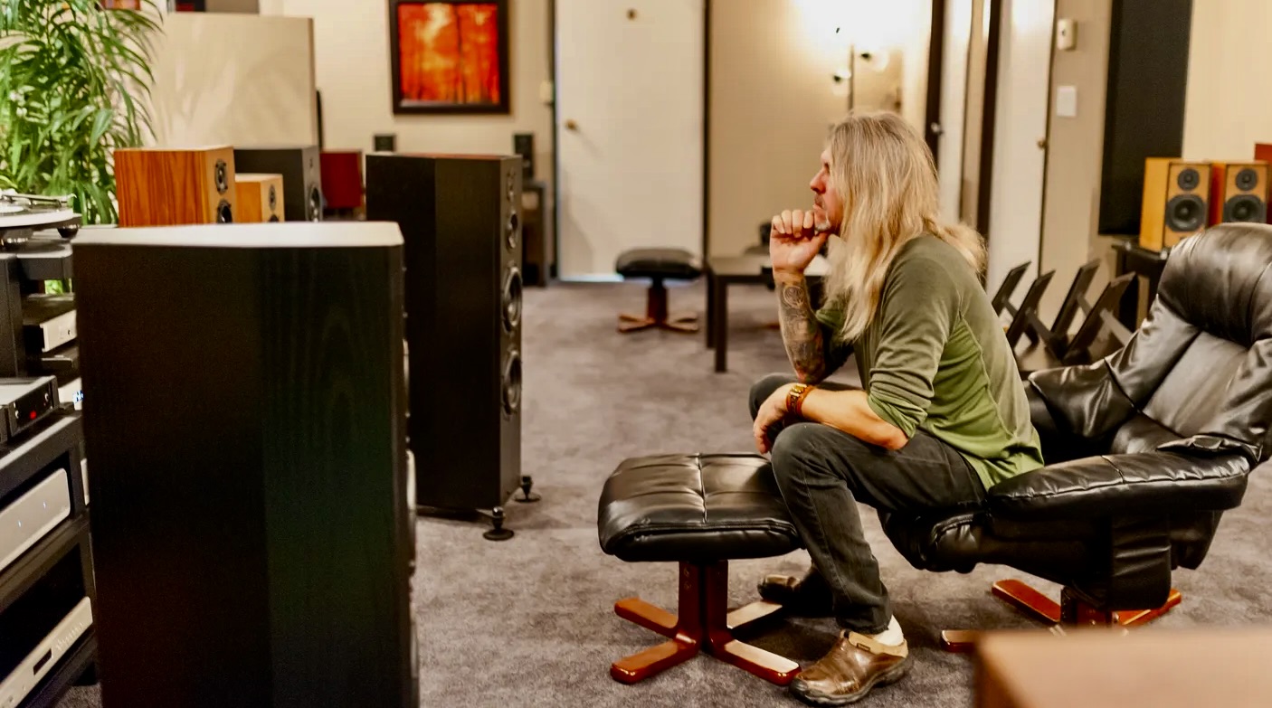A woman sitting on top of a stool in front of a tv.